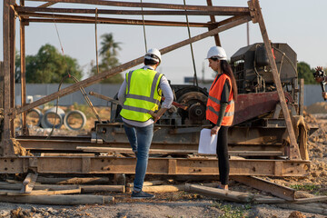 Beautiful female engineer with a male foreman wearing a protective helmet Talk about working problems, meeting together construction projects.