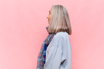 middle age woman on profile view looking to copy space ahead, thinking, imagining or daydreaming