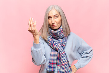 middle age woman making capice or money gesture, telling you to pay your debts!