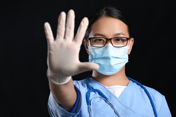 Portrait of female Asian doctor in medical mask on dark background