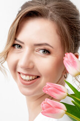 Obraz na płótnie Canvas Portrait of a happy young caucasian woman with pink tulips against a white background