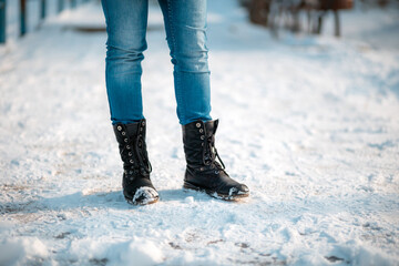 Female's feet in close-up, wearing boots with anti-slip protectors. Snow in the background. Copy space