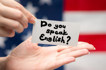 Do you speak English text on a card. American flag background.