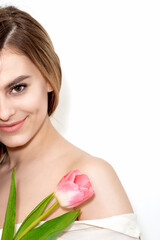 Portrait of a happy young caucasian woman with one pink tulip against a white background with copy space