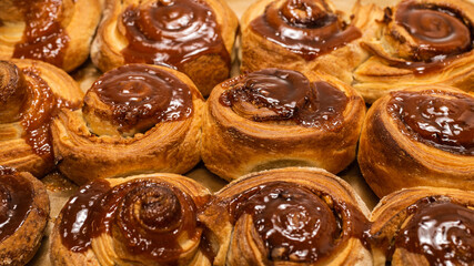 Homemade cinnamon buns with spices and caramel on parchment paper.