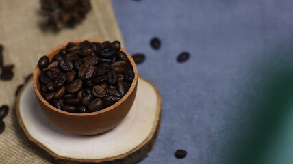 Close up photo of coffee beans on wooden plinth and burlap with bokeh foreground