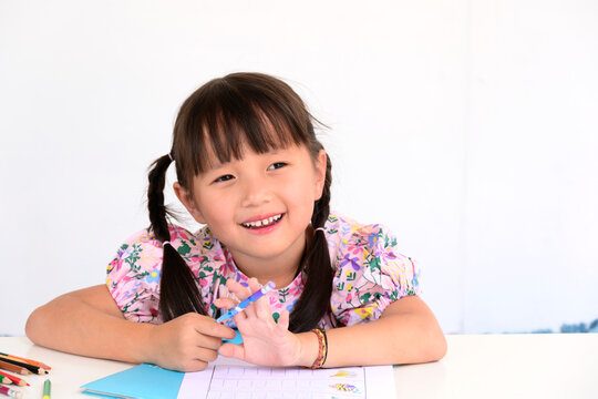 asian little girl lying drawing or made homework in the paper book for preschool kids in the home white wall