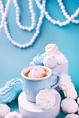Fototapeta na wymiar Espresso with froth and meringues of different colors on a blue background. Meringue. A creative shot of protein and sugar cookies. High quality photo. Copy space