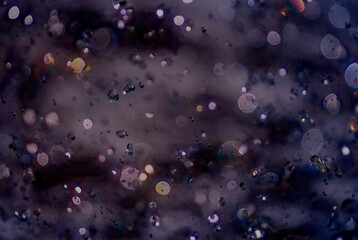 Splashing water in the rays of sunlight. Liquid purple background