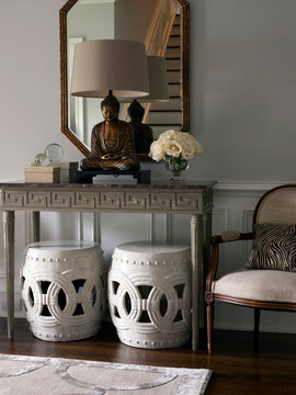 Buddha statue on console table with stools in hallway