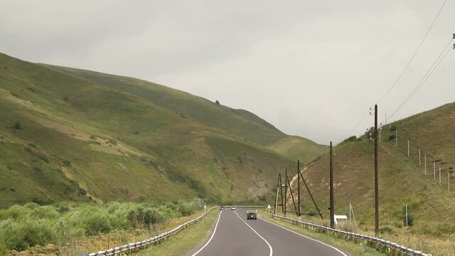 Sevan, Armenia - August 2019 - Cars rides on a paved smooth road in the middle of a mountainous area 