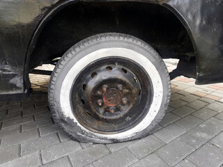 A half-lowered wheel on an old car. The tyre of the car