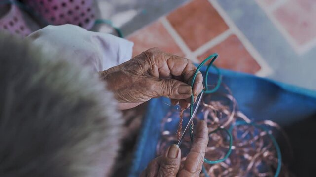 Closeup of elderly wrinkling hands remove copper from old wires plastic cover. Pre-process of recycling metal garbage. Environmental awareness. 