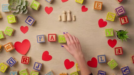 Woman hand arranging wooden cubes with word FAMILY top view - Powered by Adobe
