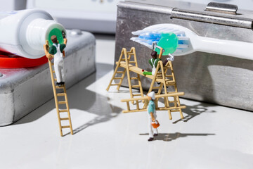 Creative concept for Dental Center and Dentist. Miniatures workers prepare toothbrush with...
