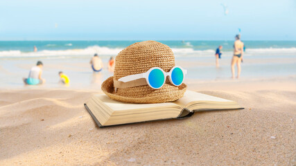 Hat and books placed on the beach. Beach activities. Vacation in summer. 