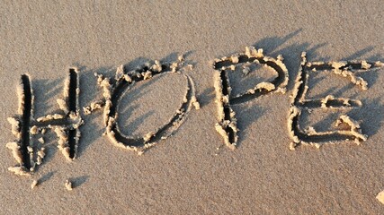Hope Word Written on Sandy Beach and Wiped Out by Sea Wave at Sunset