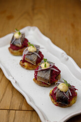 Herring canapes with pickled onions and baked potatoes. Appetizer on a platter close-up.