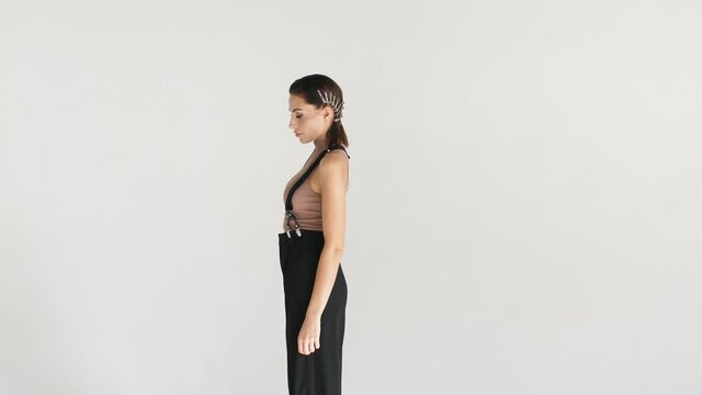 portrait of a girl in suspenders and black pants in profile posing with stylish hair styling from hairpins