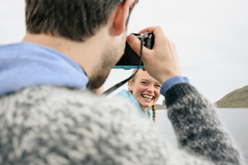 Photographer taking picture of happy woman near sea