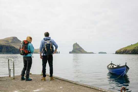 Unrecognizable hikers standing on dock near sea