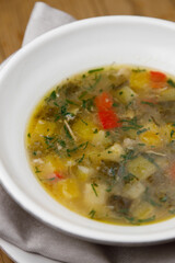 Fresh vegetable soup made from potatoes, tomatoes, pickles and herbs. Restaurant dish in a white plate close-up.