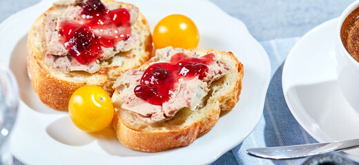 Toast with meat pate and cranberry fruit mustard with yellow cherry tomatoes and cop of coffee, close-up. Sunny morning breakfast concept. Long wide banner