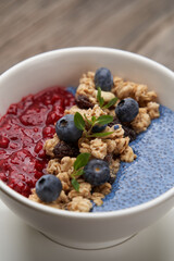 Breakfast smoothie bowl with granola on wooden background