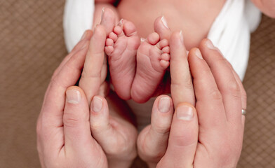 Obraz na płótnie Canvas Bare feet of newborn surrounded by family members hands