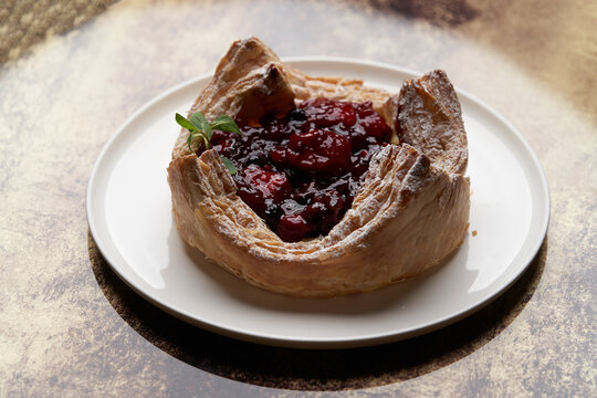 Puff pastry cake with berries on wooden background.