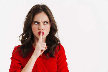 Displeased brunette girl wearing red dress showing silence gesture