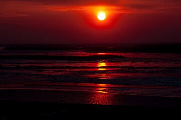Winter dark red burning sunset over frozen river with red reflection on ice surface