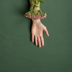 Beautiful female hand with natural flower on green background. Like veins, creative concept.