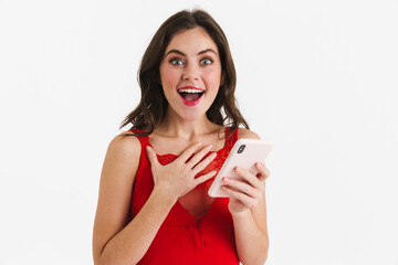 Excited beautiful girl wearing red dress using mobile phone