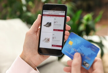 Woman with credit card using smartphone for online shopping indoors, closeup