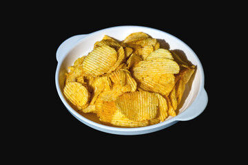 Potato chips in white plate on black background.