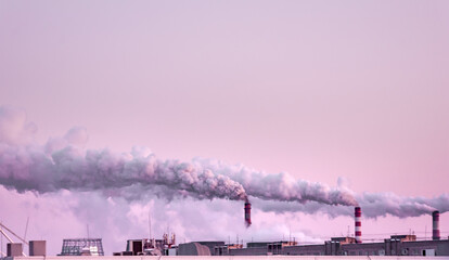 copy space with industrial chimneys with heavy smoke causing air pollution on the pink and gray smoky sky background