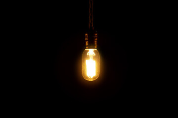 Vintage lightbulb hanging on black background. Incandescent lamp isolated on a black.