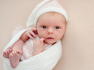 Sleepless newborn in white suit and hat