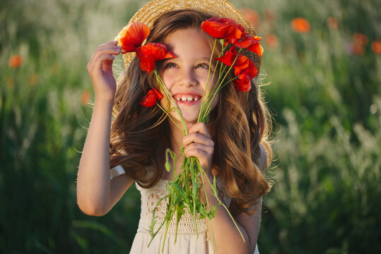 cute little girl in meadow with red poppies