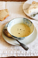 Cheese cream soup in bowl on beige linen table. Selective focus