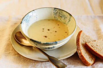 Cheese cream soup in bowl on beige linen table. Selective focus