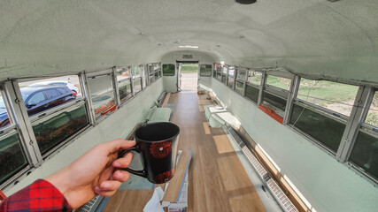 POV shot of the photographer's hand holding a tea cup of coffee inside a bus in the process of...