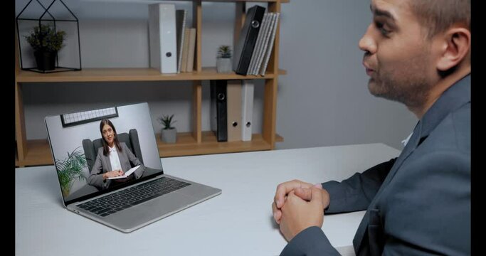Businessman talking to colleague during skype conference on laptop
