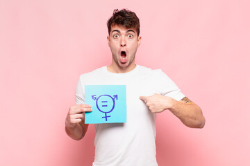 young man looking shocked and surprised with mouth wide open, pointing to self