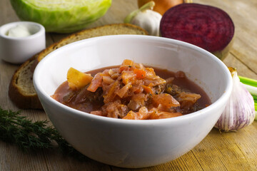 Borscht russian ukrainian traditional vegetable cabbage beetroot red soup, natural wooden background