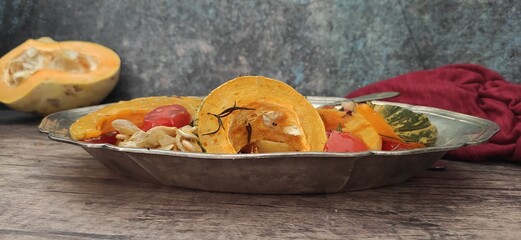 Roasted slices of pumpkin and cherry tomatoes on a silver tray