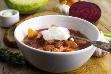 Borscht russian ukrainian traditional vegetable cabbage beetroot red soup, natural wooden background