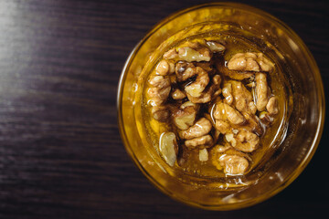 Walnut close-up in honey on a dark background in a glass