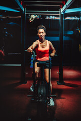 Beautiful fit woman training by riding a bicycle in a gym